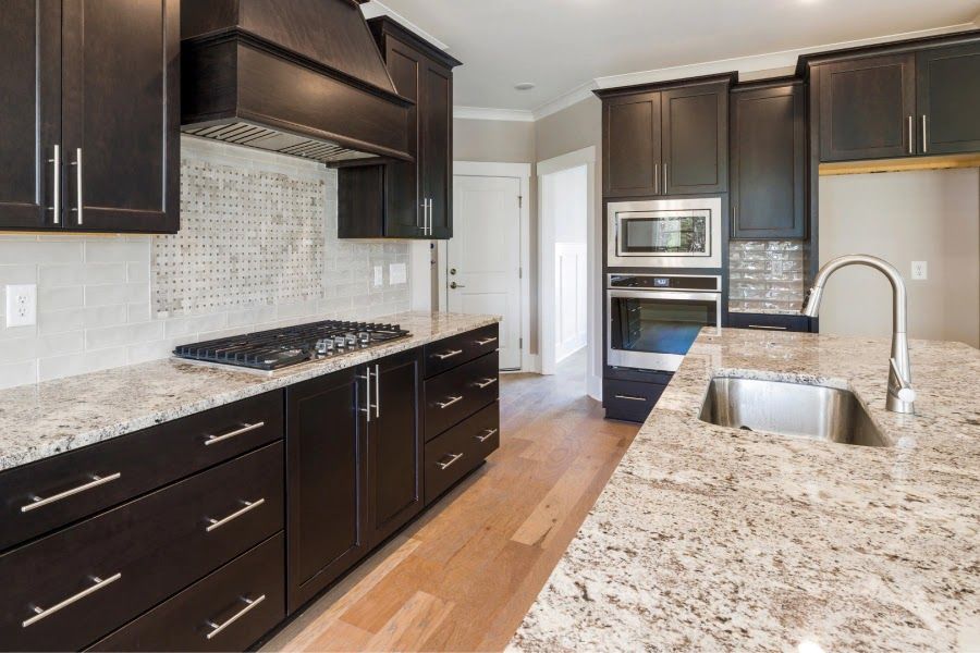Dark kitchen with granite countertops, stainless steel appliances, and wood cabinets.