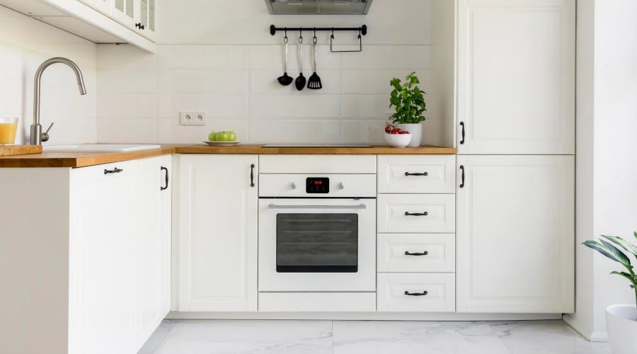 White kitchen with wooden countertops, white cabinets, and oven.
