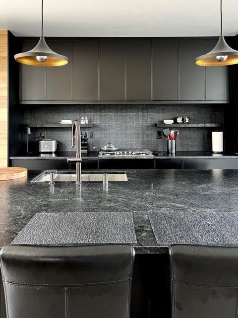 Modern kitchen with black cabinets, countertop, and pendant lights.