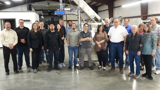 A group of people are posing for a picture in a factory.