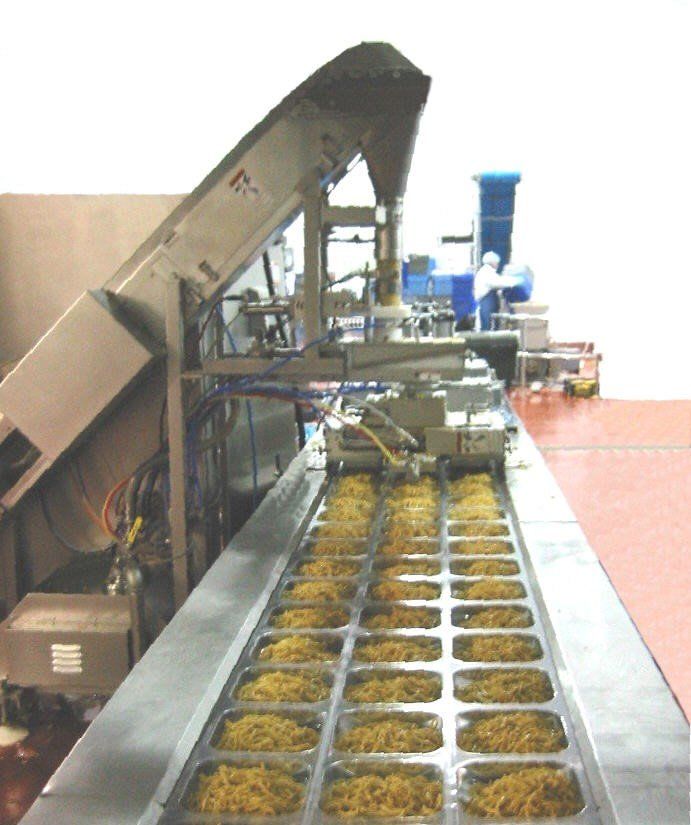 A conveyor belt filled with noodles in a kitchen