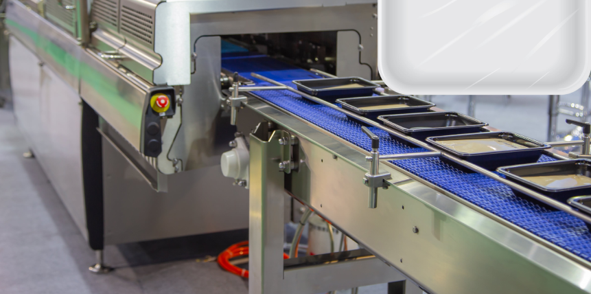 A conveyor belt filled with plastic trays in a factory.