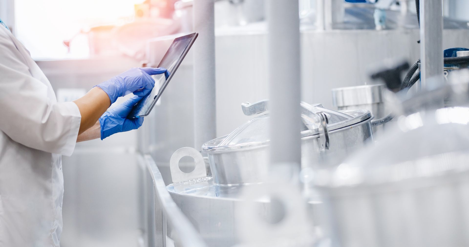A scientist is using a tablet in a factory.