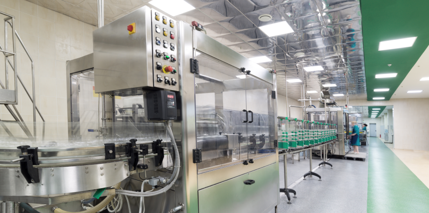 A stainless steel machine is sitting in a clean room in a factory.