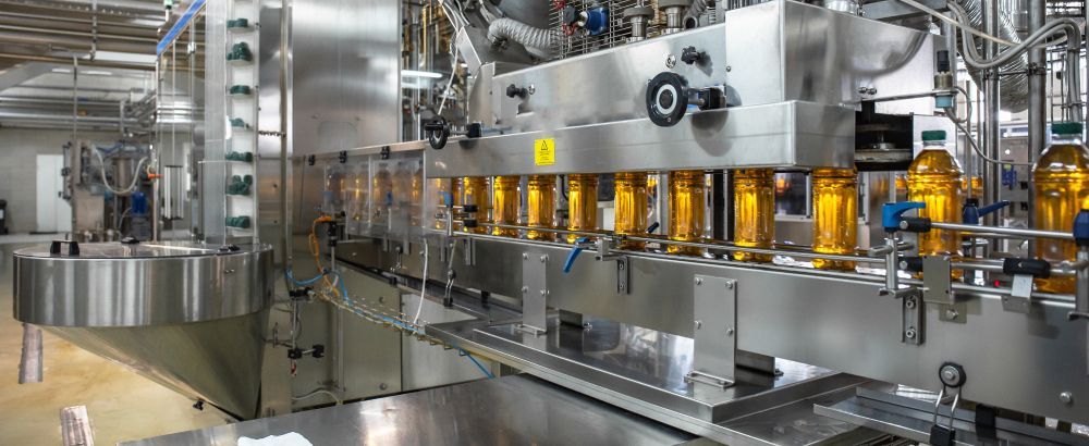 A large machine is moving bottles of liquid on a conveyor belt in a factory.