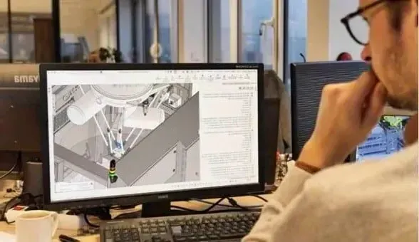 A man is sitting at a desk looking at a computer screen.