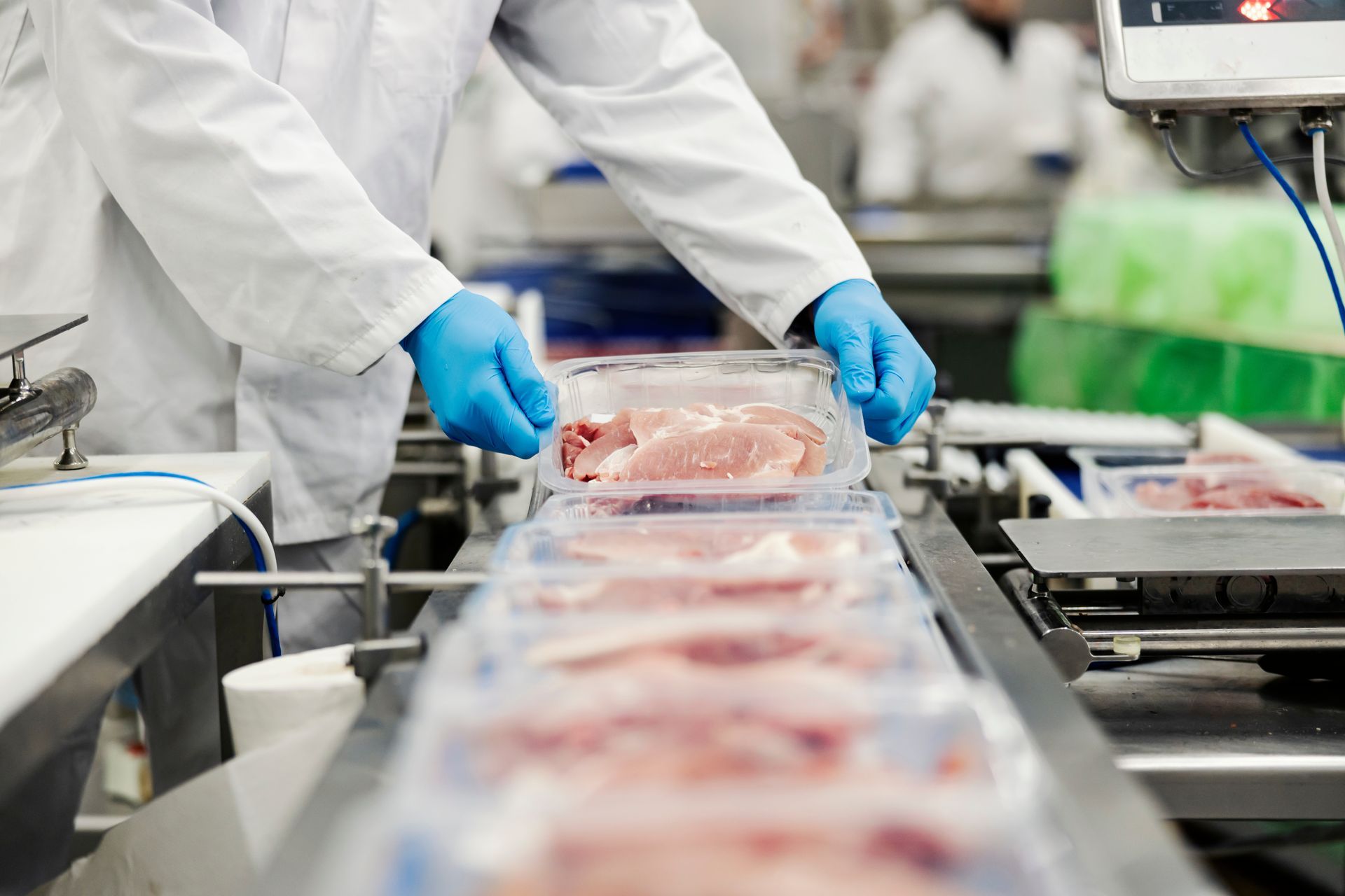 A man is packing meat on a conveyor belt in a factory.