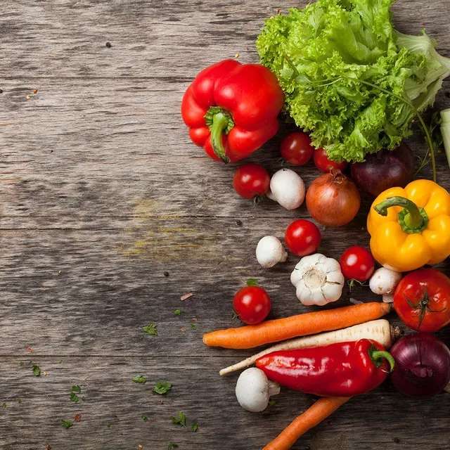 A wooden table topped with a variety of vegetables.