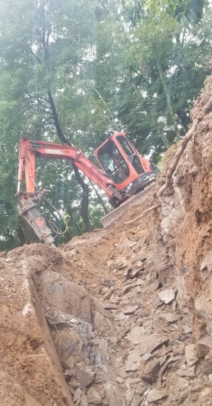 A red excavator is sitting on top of a pile of dirt.