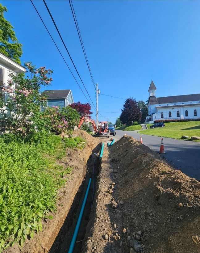 A pipe is being installed in the dirt next to a church