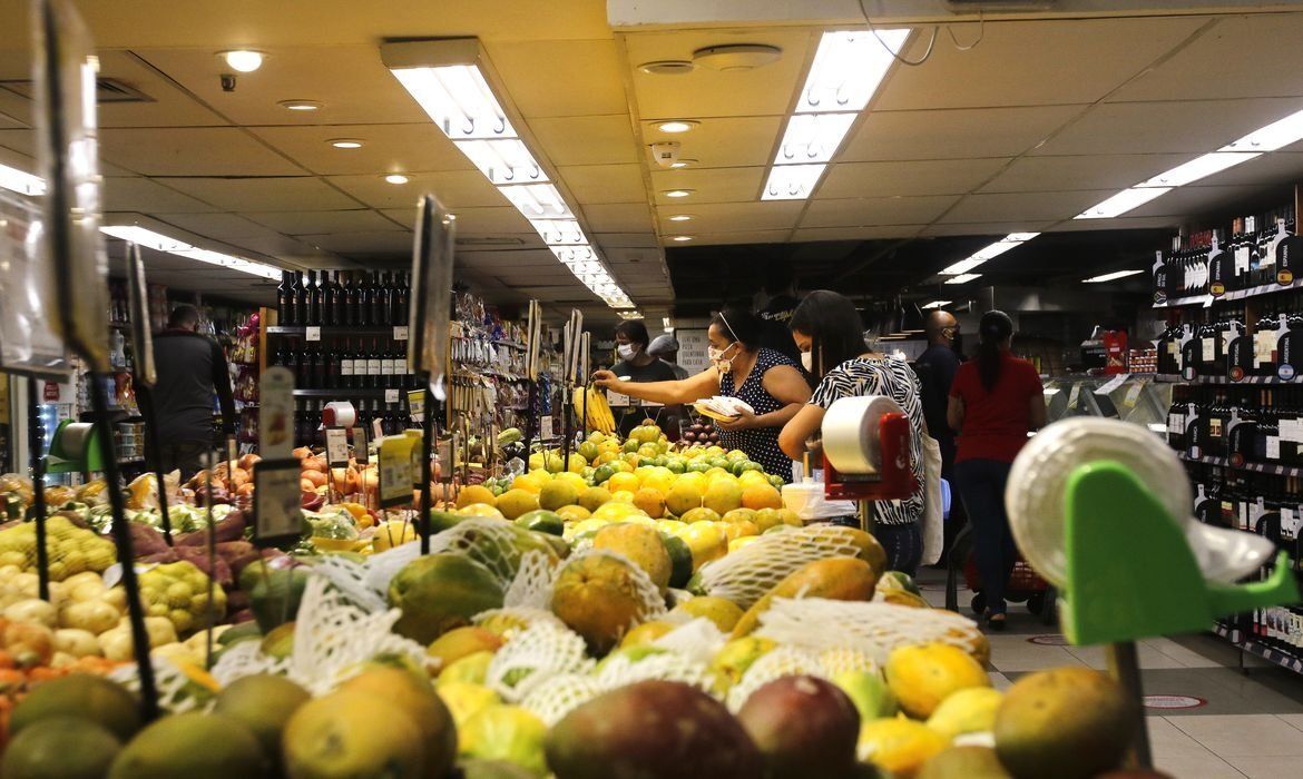 Espaço de supermercado com frutas e pessoas.