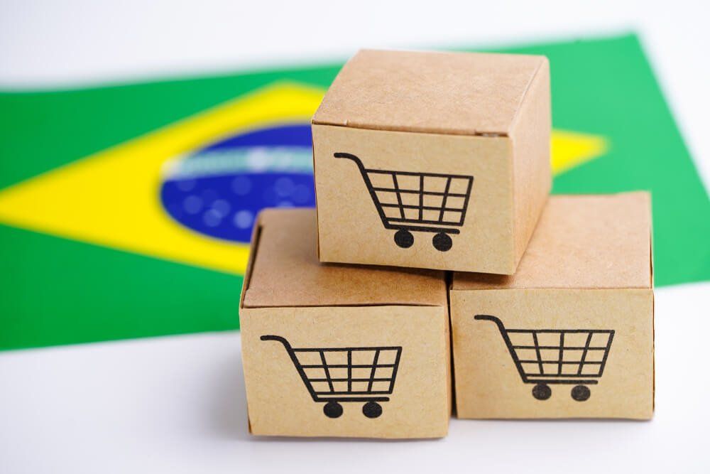 Caixas de cartão com o símbolo de carrinho de compras sobre mesa com bandeira do Brasil