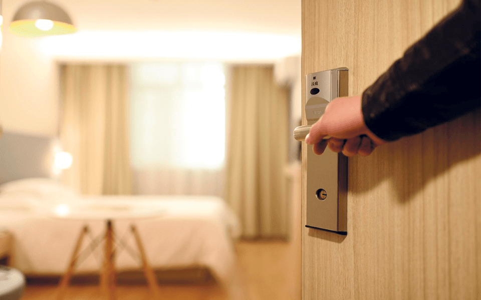 Pormenor de mão de homem a abrir porta de quarto de hotel