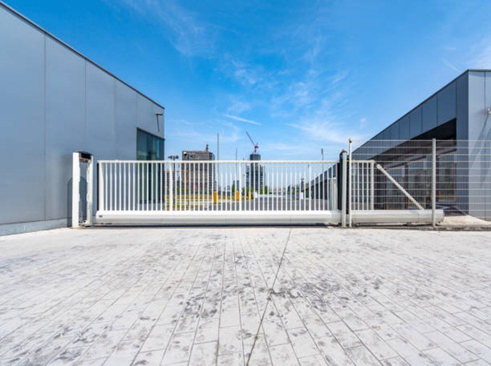White sliding gate in front of two buildings on a sunny day.