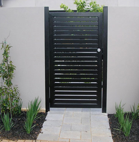 Black slat gate in a gray wall, leading to a stone path.