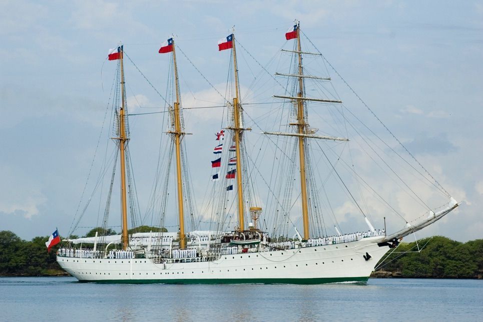 A large sailboat with flags on the masts is in the water