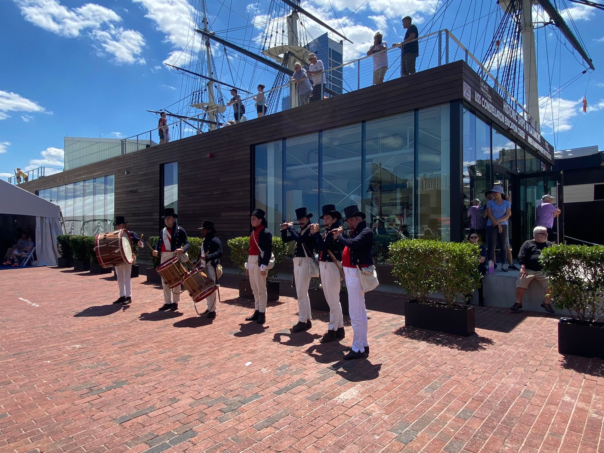 A group of men are standing in front of a building playing drums.