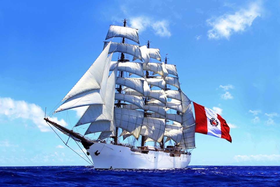 A sailboat with a flag on the side is sailing in the ocean.