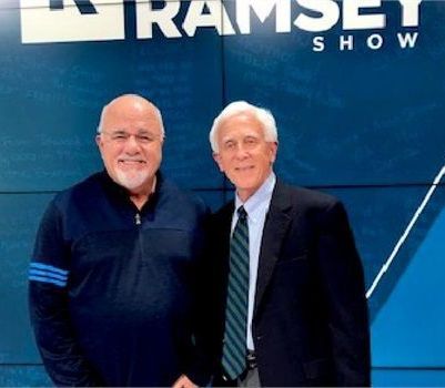 Two men standing in front of a ramsey show sign