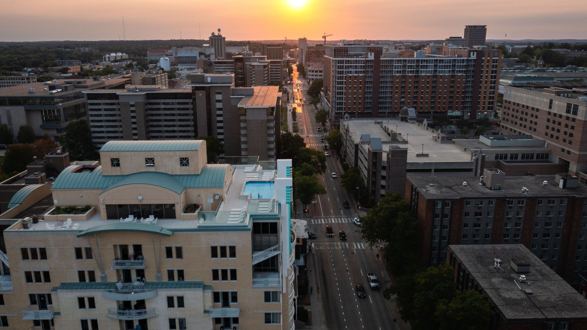 An aerial view of a city at sunset with a large building in the foreground.