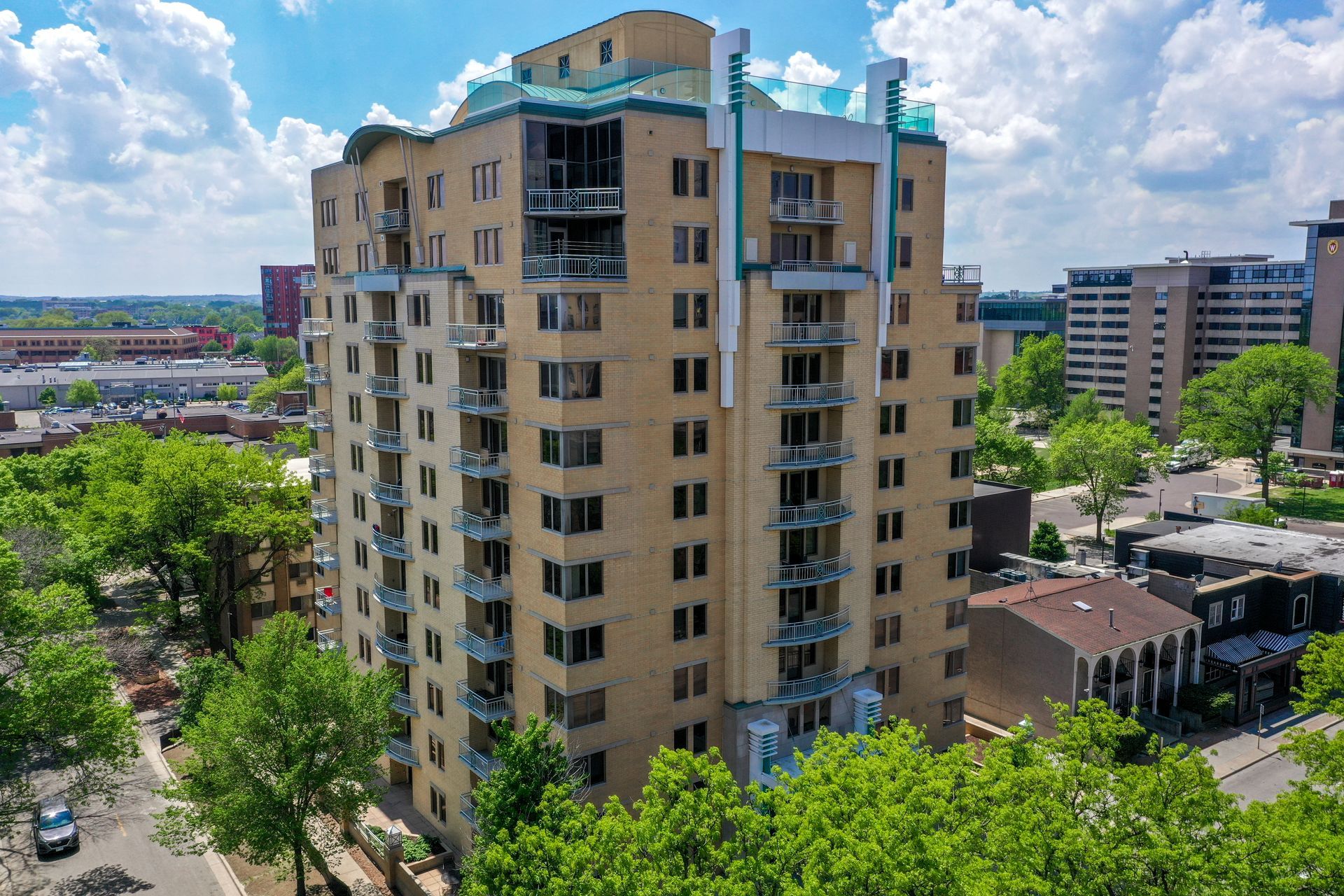 An aerial view of a tall building surrounded by trees in a city.