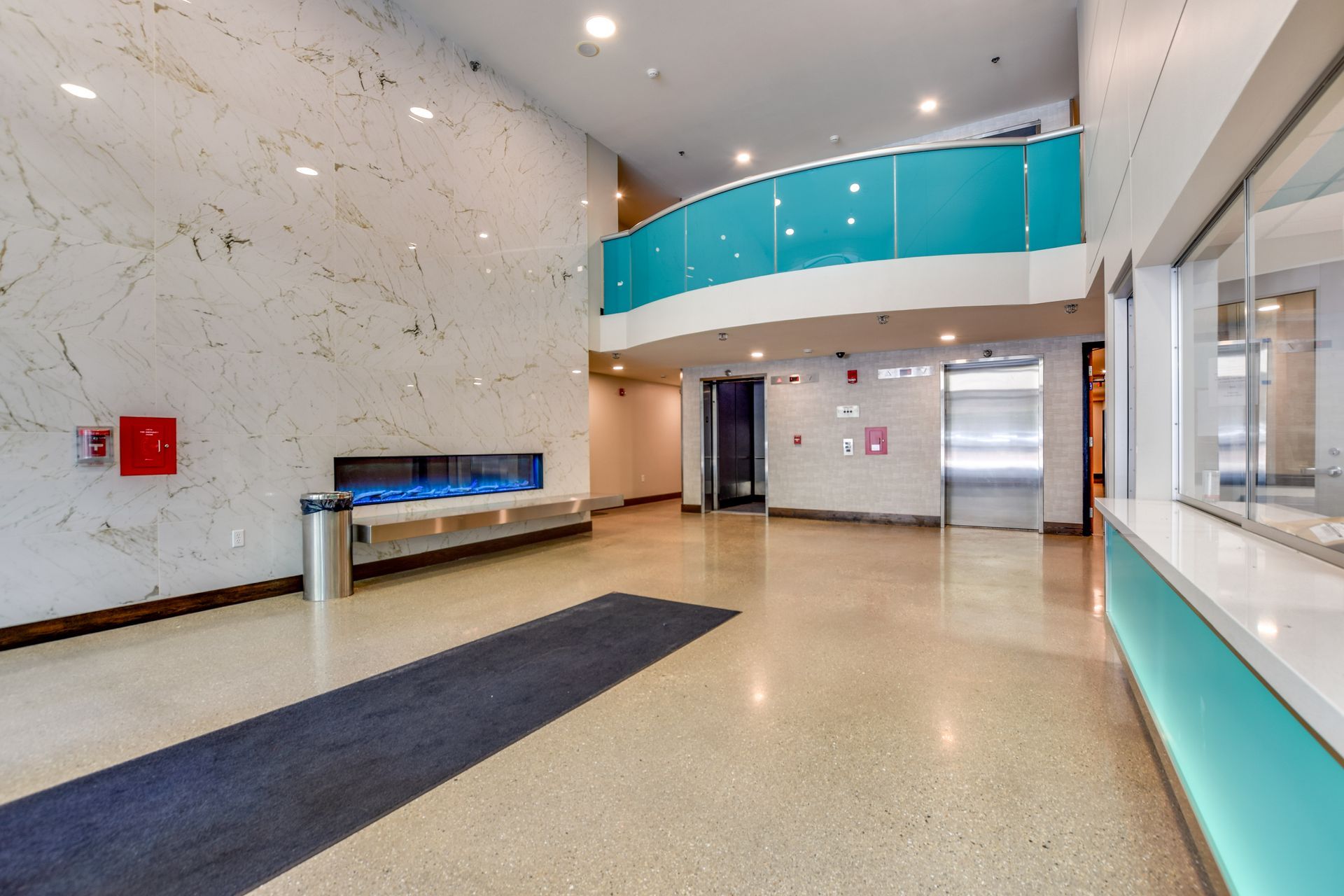 A large lobby with a blue railing and a bench