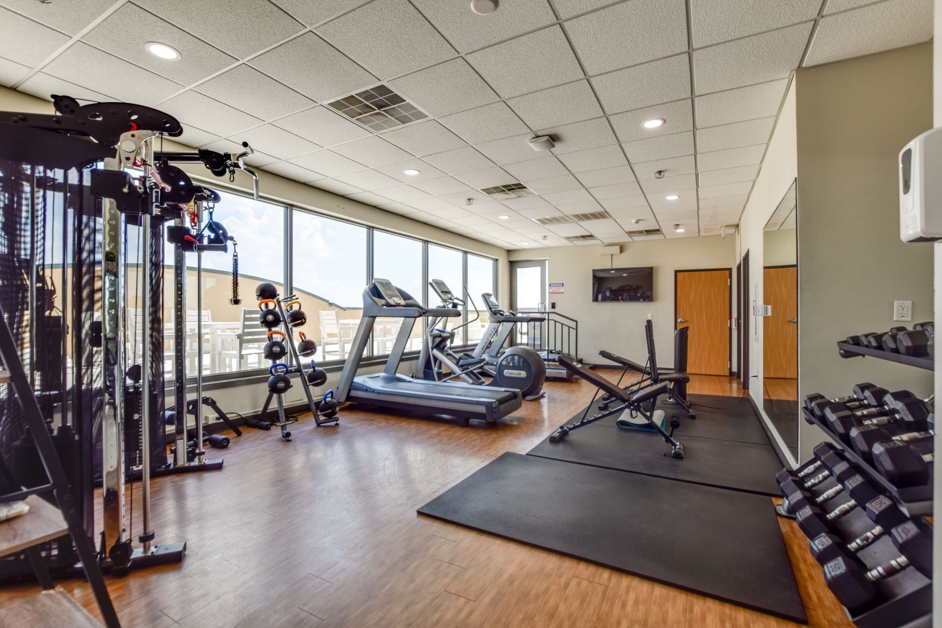 A large gym with treadmills , dumbbells , and a large mirror.