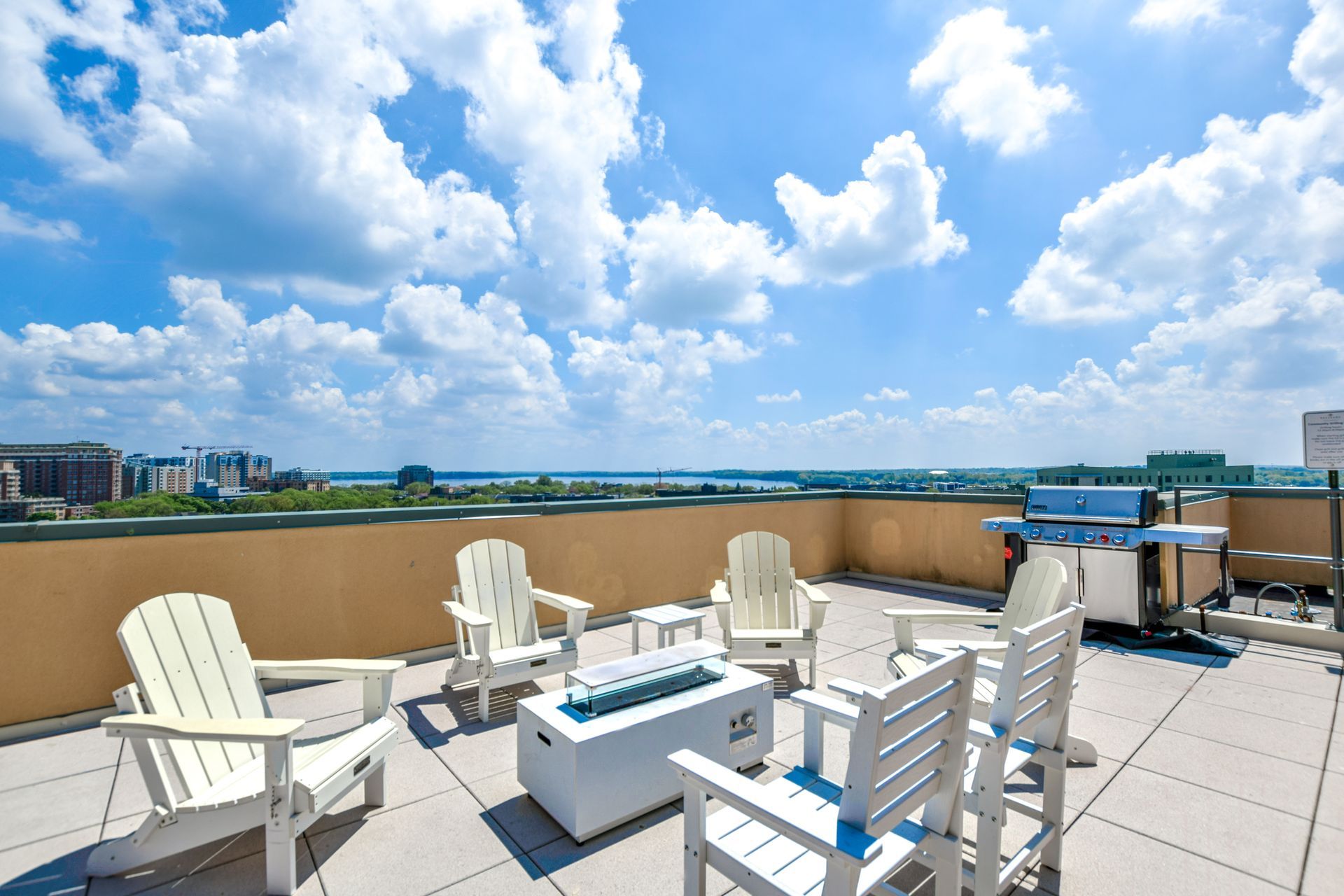 A rooftop patio with chairs and a fire pit