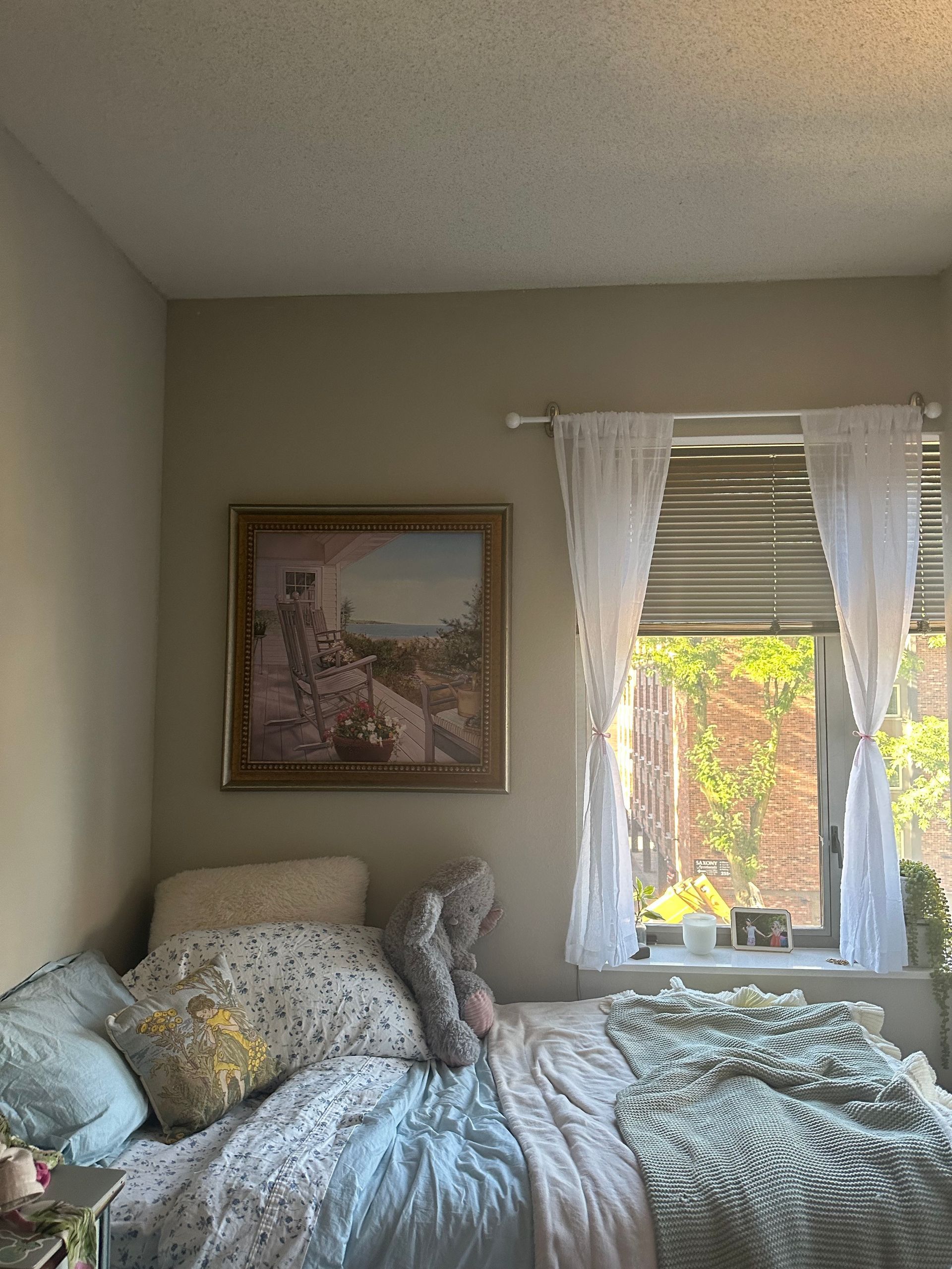 A bedroom with a bed , window and a painting on the wall.