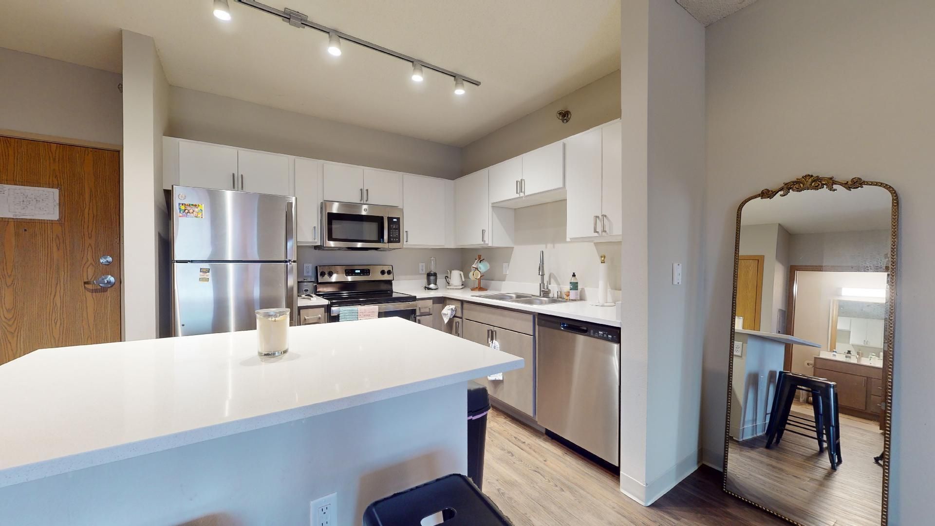 A kitchen with stainless steel appliances and a large mirror.
