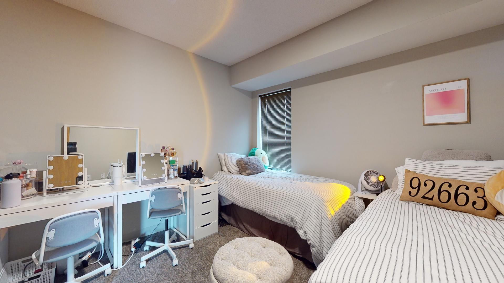 A bedroom with two beds , a desk and a mirror.