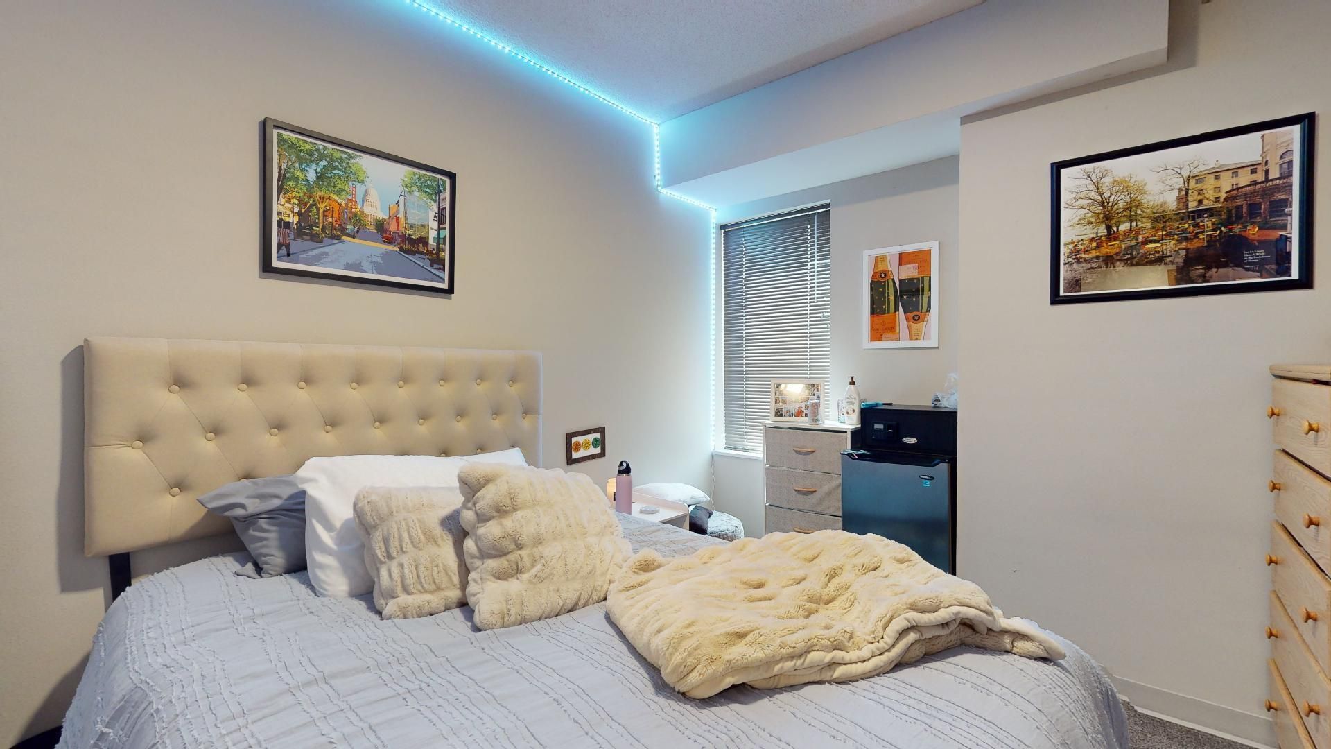 A bedroom with a bed , dresser , and two paintings on the wall.