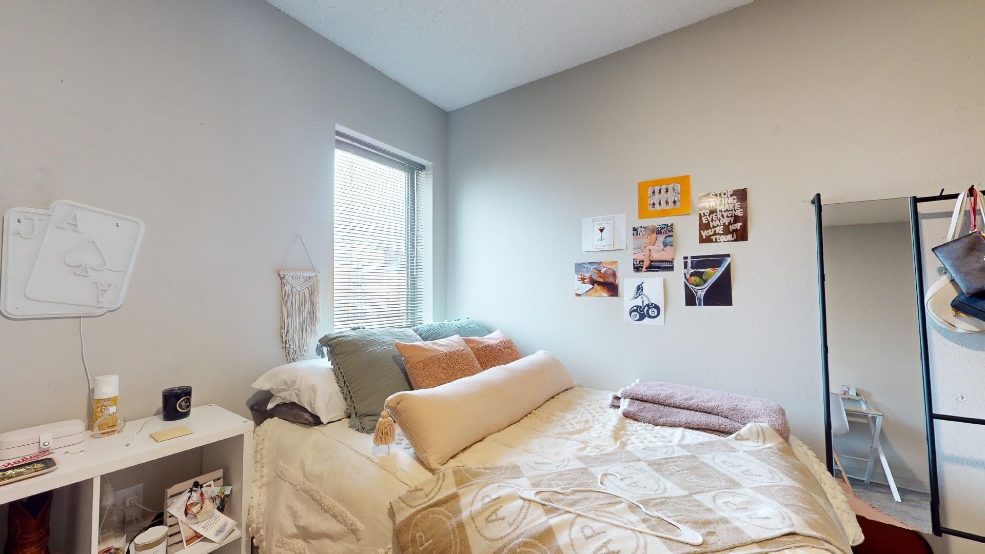 A bedroom with a bed , dresser , mirror and window.