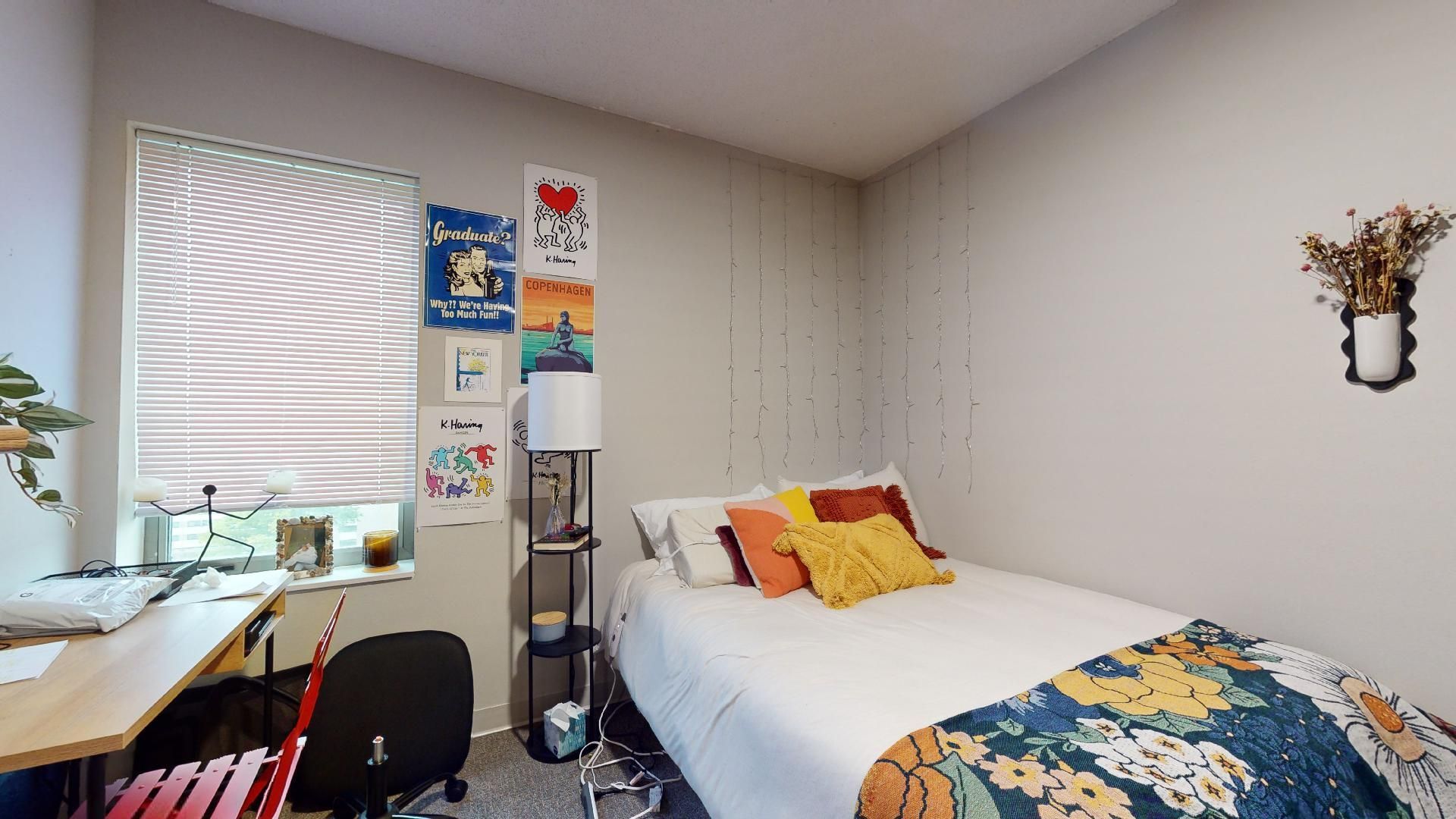A bedroom with a bed , desk , chair and window.
