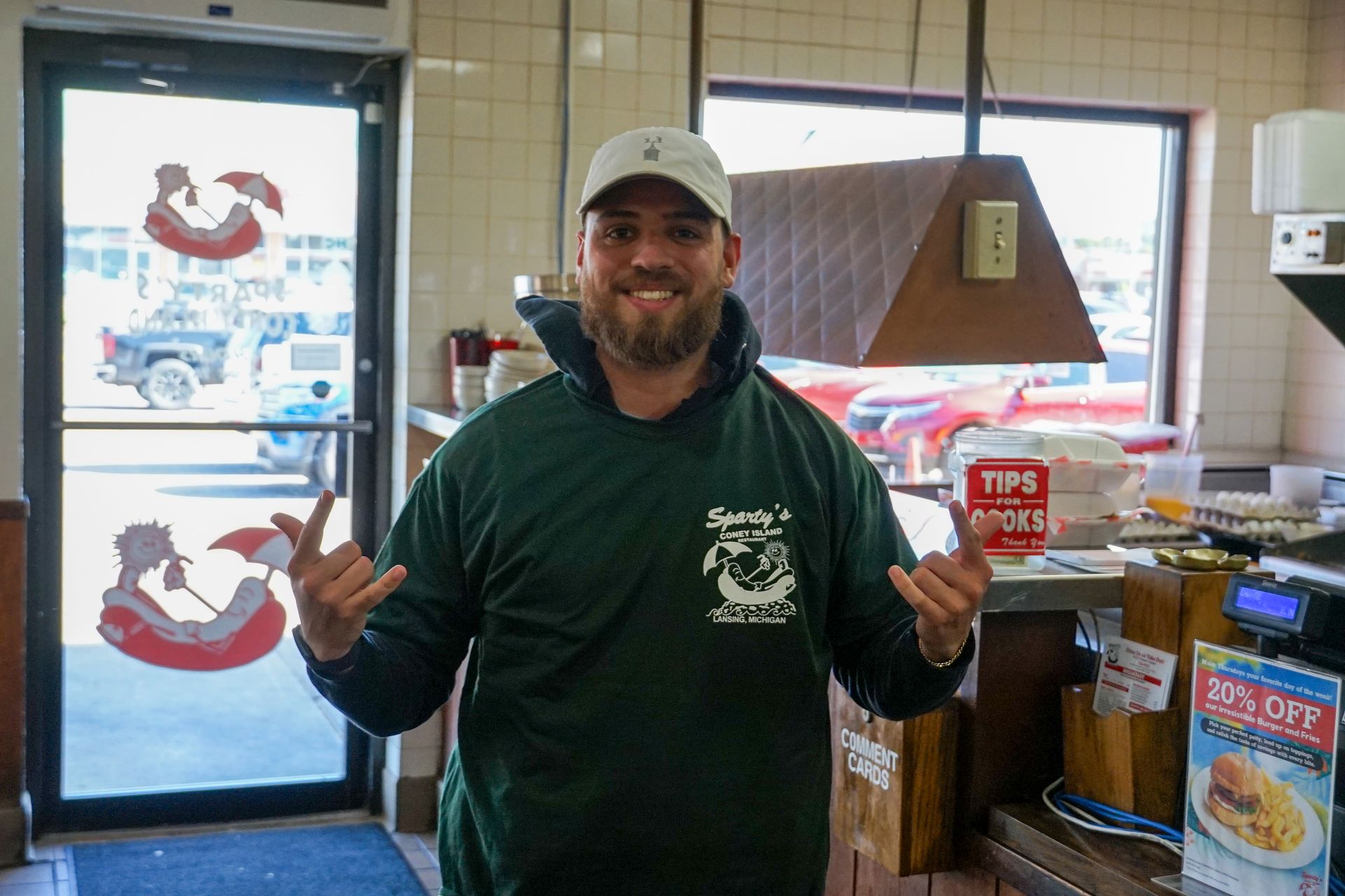 A man in a green shirt is standing in a restaurant.