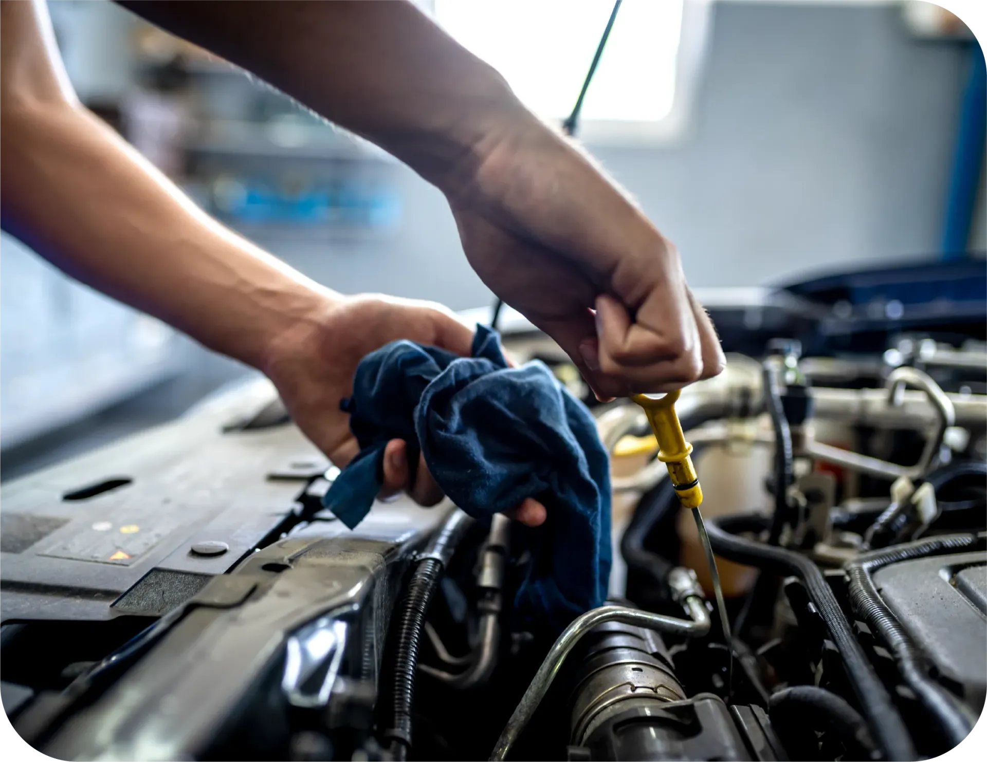 A person is checking the oil level of a car with a towel.