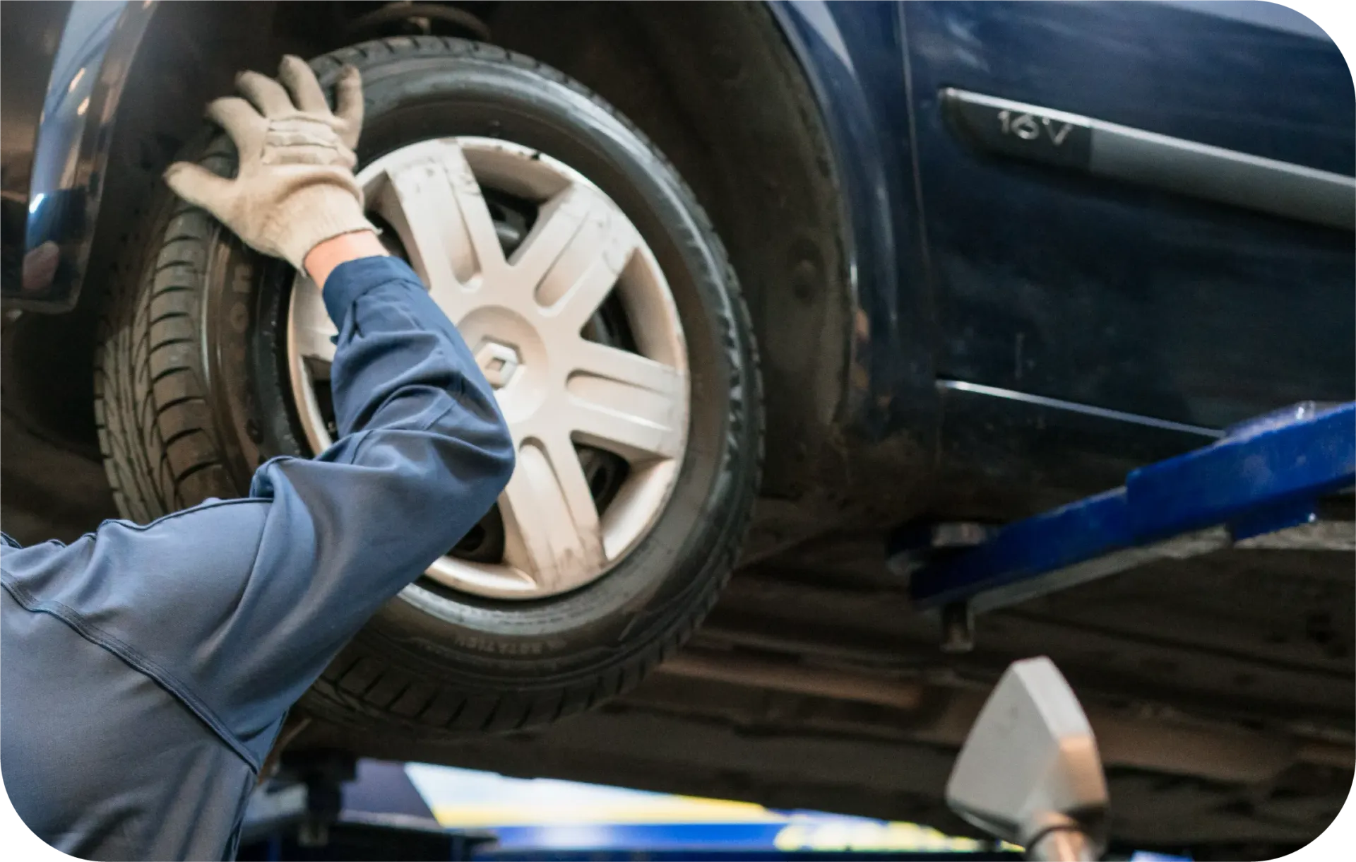 A man is changing a tire on a car on a lift.