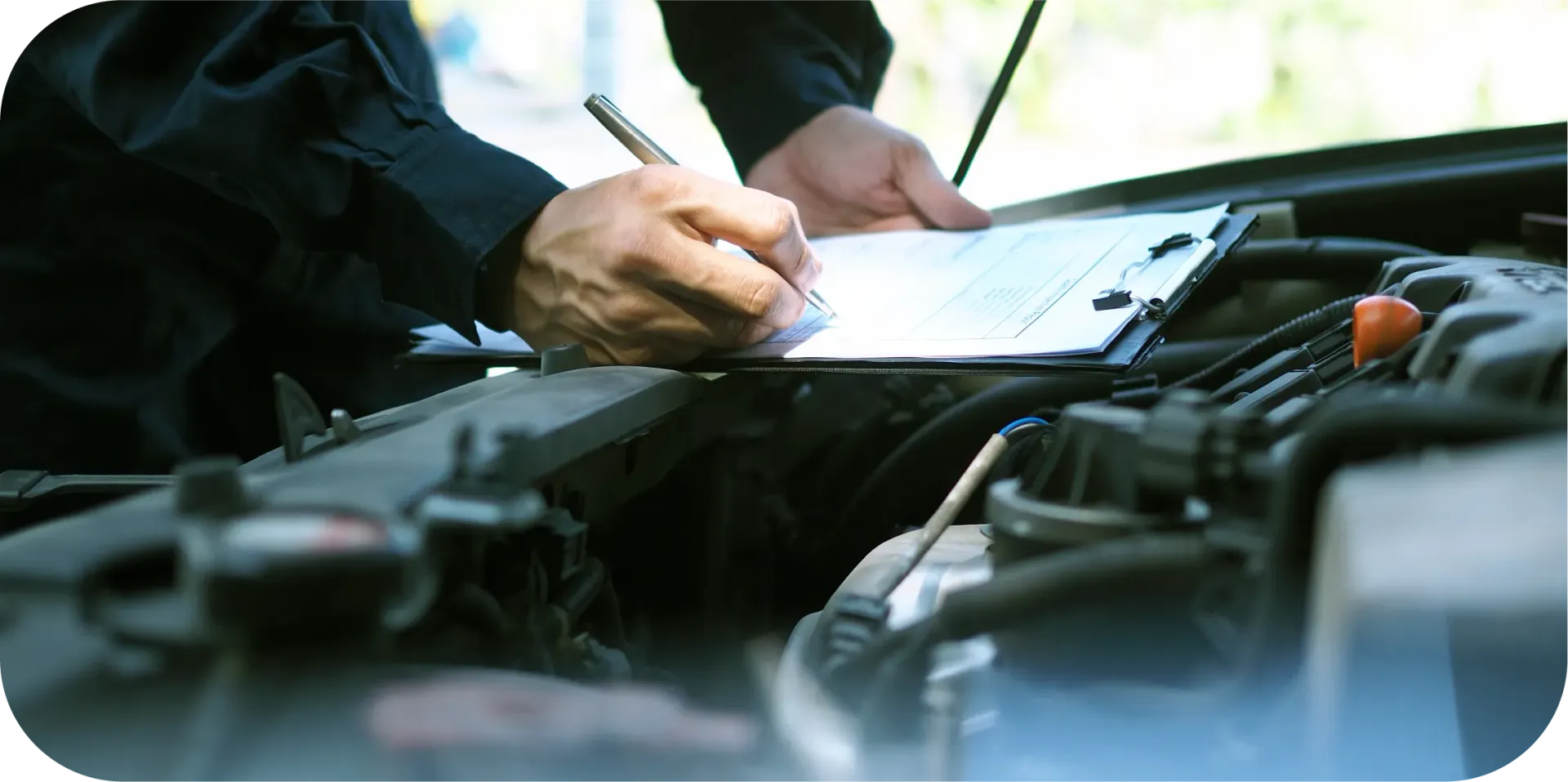 A man is writing on a clipboard while looking under the hood of a car.