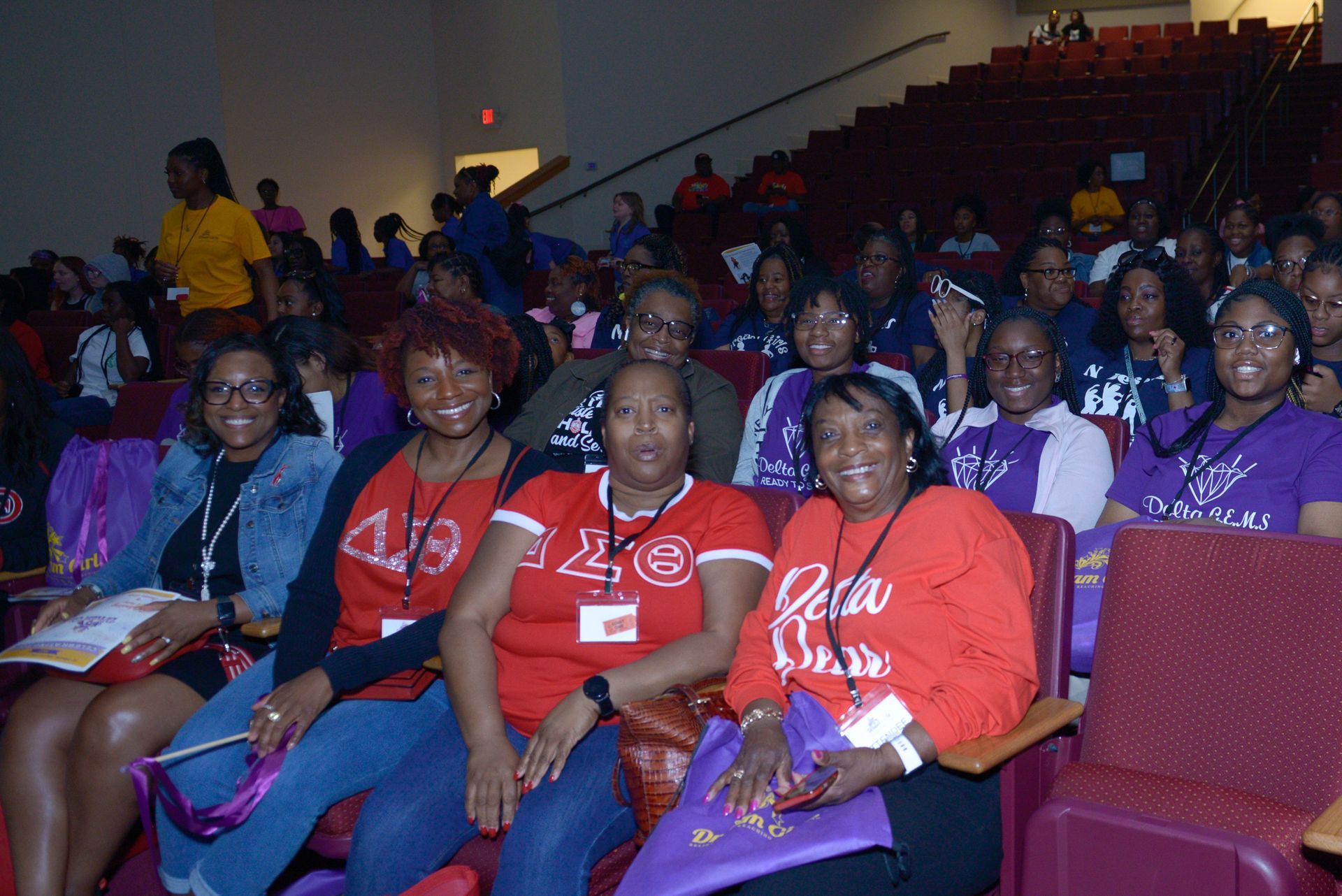 a group of women are sitting in an auditorium wearing delta sigma shirts