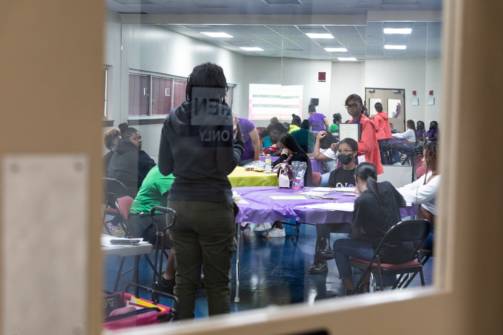 a group of people are gathered in a room with a sign that says