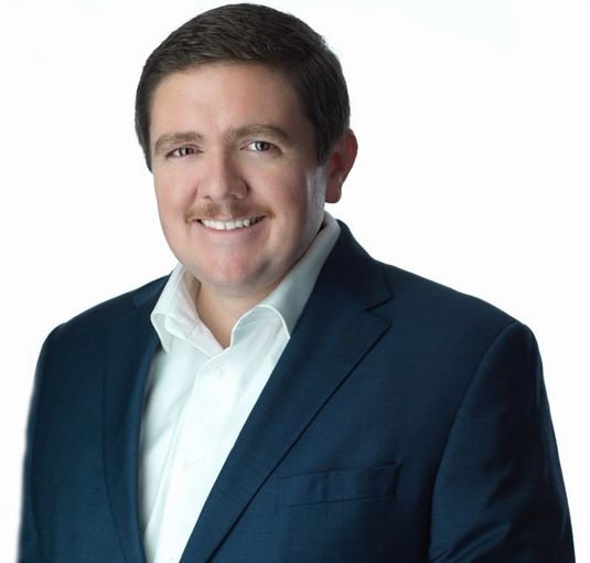 A man in a suit and tie is smiling for the camera.
