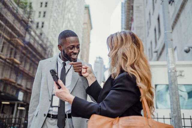 A woman is taking a picture of a man in a suit and tie.