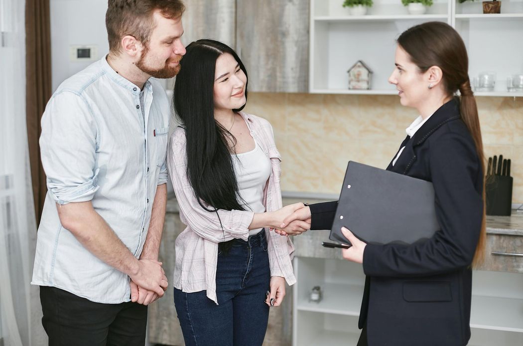 A woman is shaking hands with a man and woman in a kitchen.