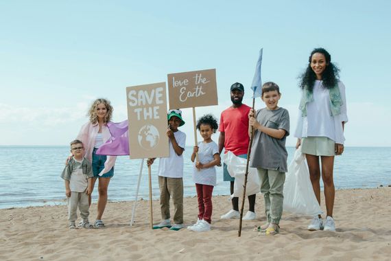 A group of people are standing on a beach holding signs.