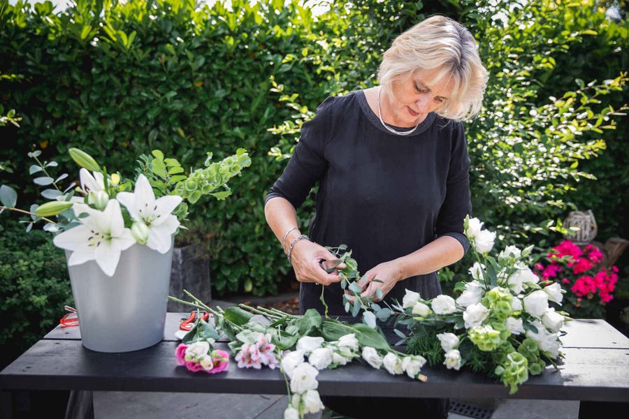 Een vrouw schikt bloemen op een tafel