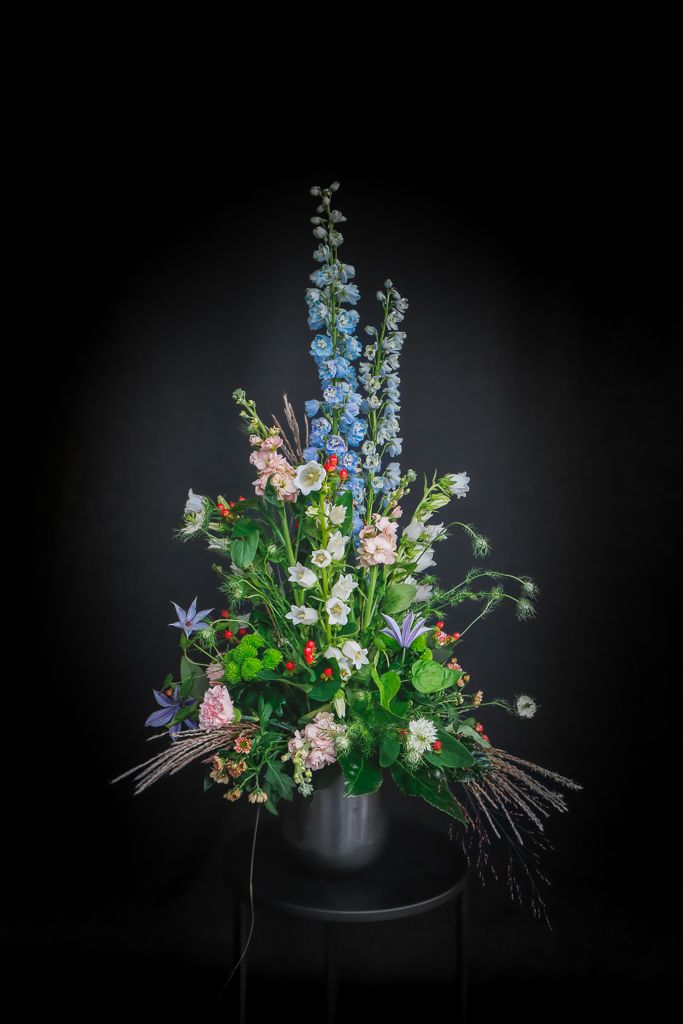 Een vaas gevuld met bloemen op een tafel met een zwarte achtergrond