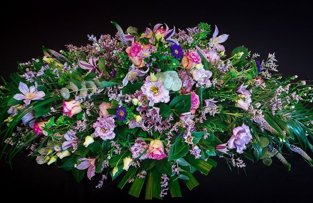 Een groot  bloemstuk roze en paarse bloemen op een zwarte achtergrond