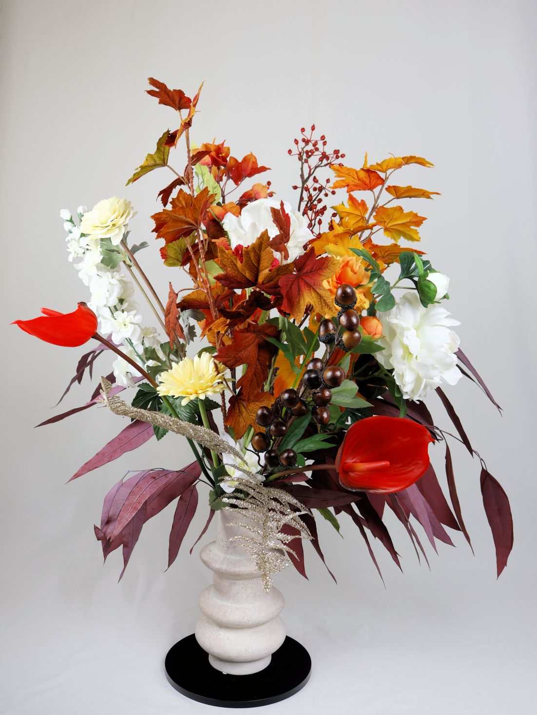 Een vaas gevuld met gele en witte zijdenbloemen op een tafel