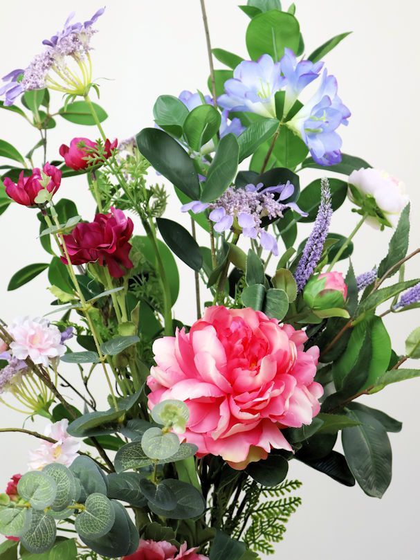 Een vaas gevuld met gele en witte zijdenbloemen op een tafel
