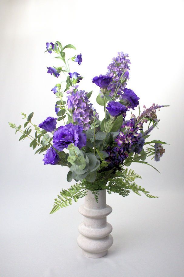 Een vaas gevuld met paarse en witte zijdenbloemen, altijd verse bloemen.